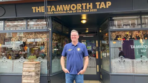 George Greenaway wearing a blue polo shirt and jeans with his hands in his pockets standing outside the Tamworth Tap