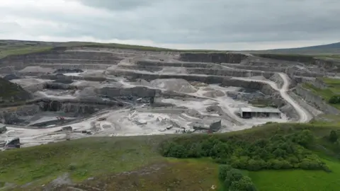 An aerial view of Horton in Ribblesdale quarry showing a deep quarry up against the green Dales landscape.