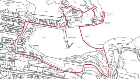 North Devon Council The image shows a black‑and‑white map of Ilfracombe Harbour and the surrounding streets, with a thick red line marking the boundary of a specific area. The map includes roads, buildings and sections of the coastline, with the harbour basin in the centre. The red outline runs around the waterfront, through nearby residential streets and across the headland before looping back inland. It highlights the zone covered by the order around the harbour and the adjacent streets.