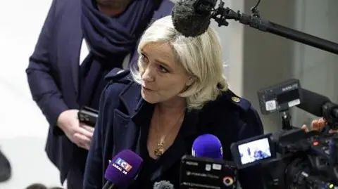 AFP French far-right Rassemblement National (RN) Member of Parliament Marine Le Pen talks to the press as she arrives for the closing arguments hearing in the trial on suspicion of embezzlement of European public funds, at a court in Paris on November 13, 2024