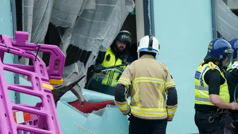 PA Media Emergency services workers inspect damage to a window at the Holiday Inn Express in Rotherham, after rioters caused disorder on 4 August