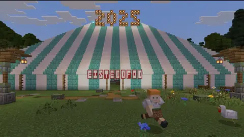 Wrexham Games Team/Minecraft A virtual Minecraft world displaying a blue and white striped Eisteddfod tent with the number 2025 on top.