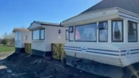 LDRS White static caravans next to a corrugated iron potato barn