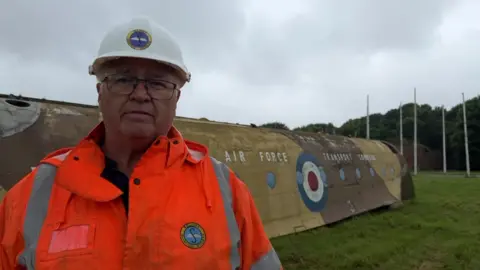 Dougie Kerr, from Solway Aviation Museum, standing in front of a section of the Blackburn Beverley. The RAF logo can be seen on the side of the vehicle.