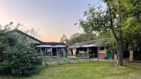Location plan for land at Clouds Hill Farm, Oxshott. The image shows a garden with trees and old buildings.