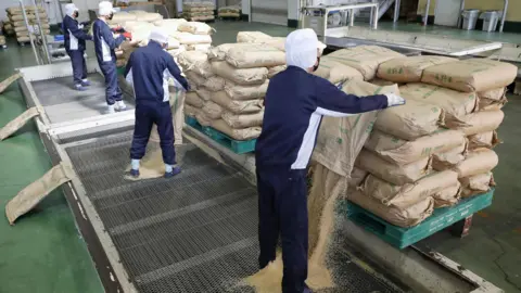 Getty Images Bags containing Japanese government's emergency stockpile rice are brought to a rice mill.