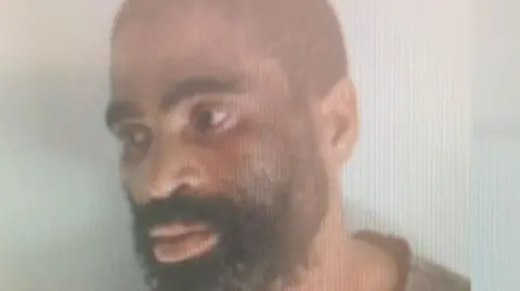 SAPS A police image of James Neo Tshoaeli, who sports a beard and looks away from the camera