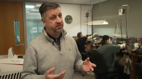 Dan Towse, a man in a grey quarter zip with brown and grey hair.