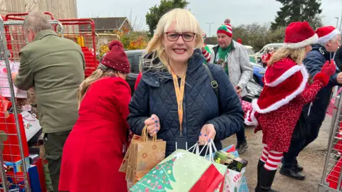 Sally Hillyear who is the Director of Fundraising at Southampton Hospitals Charity is standing in the hospital car park surround with bags of Christmas presents.