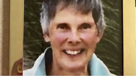 A framed photo of Diana Walker, who smiles at the camera wearing a blue top 