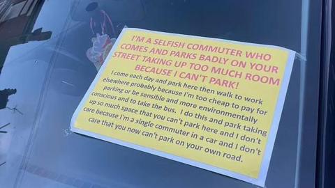 A yellow note taped to a car windscreen