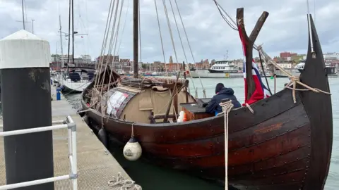 A big brown ship parked in a marina.