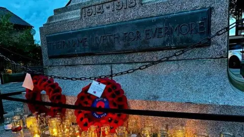 Carnforth Town Council lit candles in glass jars and two wreaths of poppies placed at the bottom of the war memorial sculpture