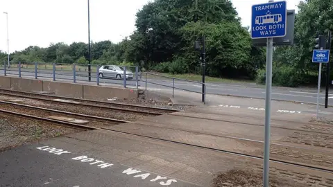 RAIB The Staniforth road crossing where the teens had been hit. It says "look both ways" on the floor in white and has two blue signs saying "tramway, look both ways". There are no barriers.