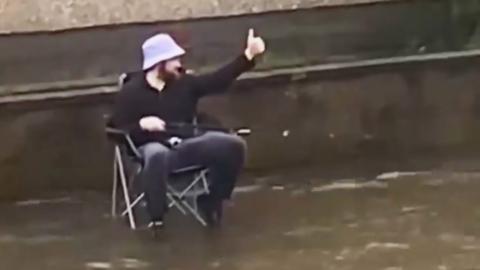 Man sits on a chair in a flooded street