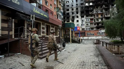 Reuters Members of the White Angel unit of Ukrainian police officers who evacuate people from the frontline towns and villages, check an area for residents, amid Russia's attack on Ukraine, in the frontline town of Pokrovsk in Donetsk region, on 21 May 2025.