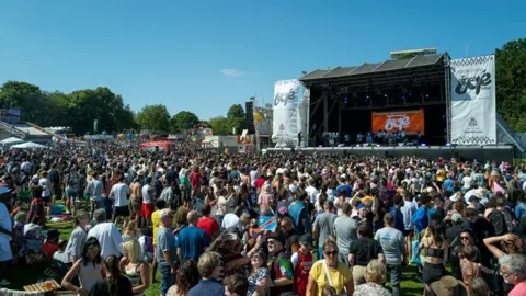 A packed crowd chat and drink as they wait for a band to take the main stage