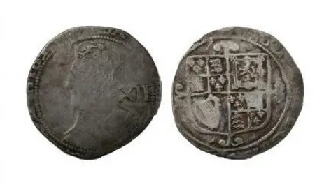 The British Museum's Portable Antiquities Scheme A worn silver coin. The left image shows a faded image of Charles I on the coin. Details of his crown can be made out. The left image shows the reverse side of the coin and shows a coat of arms, which include a harp and a lion. The coat of arms is off-centre.