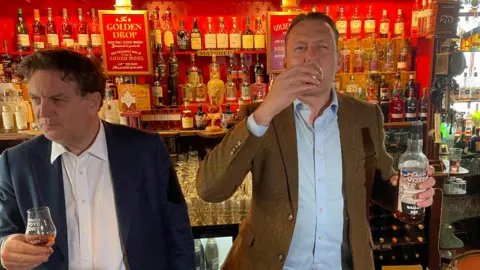 Russell Findlay (right) drinks a glass of whisky at the Canny Man's pub in Edinburgh, with Shadow Chancellor Mel Stride on his left