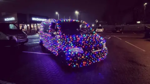 Scott Dickens The van parked in a fast food restaurant car park at night, showing how the rainbow lights cover every inch of it apart from the windows, windscreen and headlights.