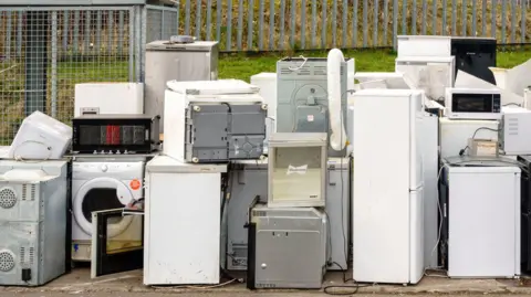 A selection of fridges and freezer piled up