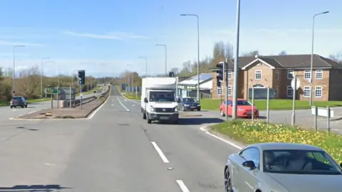 Google streetview of junction with vehicles passing by a two-storey property.