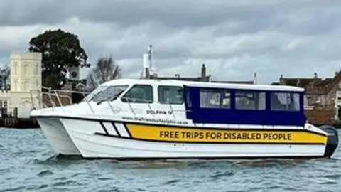 Dolphin IV with inscription on, reading "Free trips for disabled people". It is a cloudy day.