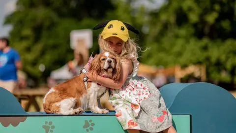 Dogstival An image of a little girl cuddling her dog and smiling at the camera