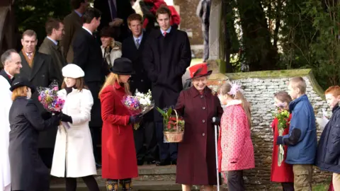 Getty Images Royals after the traditional Christmas Day service gather on steps of church. Queen Elizabeth II is helped by her granddaughters Princess Beatrice And Princess Eugenie as she receives flowers and gifts from children in the crowd. 