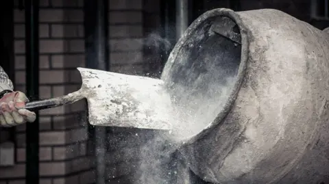 Getty Images A stock image of dry concrete being shovelled into a cement mixer
