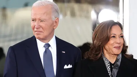 Getty Images Biden in a dark suit looking one way and Harris wearing a coat and scarf looking in a different direction