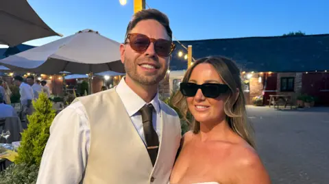A man and a woman stood looking at the camera smiling