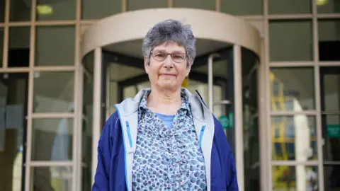 Diane Warner, wearing a blue blouse and jacket, outside court