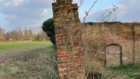 Church Commissioners for England/City of York Council A garden wall of red brick is shown leaning precariously