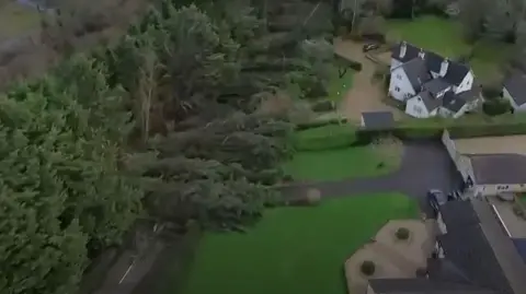 An aerial view of large houses collapsed across a road and onto people's gardens