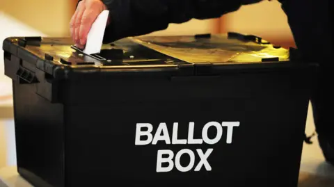 Black ballot box with a hand placing a paper inside it