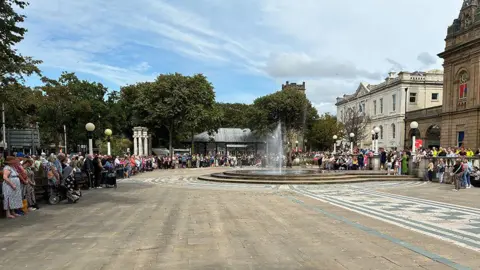 People lined the public space outside the Atkinson art gallery in Southport town centre on Lord Street for a three-minute silence two years after the Southport knife attacks. It was a sunny day.