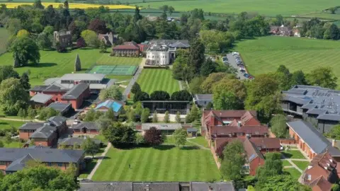 Squires and Brown An artists impression of the school's grounds once plans are completed which show a large green space with various buildings spaced between the trees.