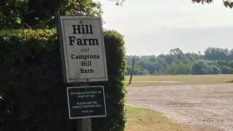 James Hore/BBC Sign for Hill Farm and field surrounded by trees