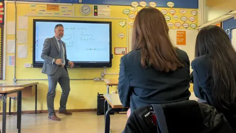 BBC News/Hayley Clarke Principal Simon Hart stands at the front of a classroom, teaching maths