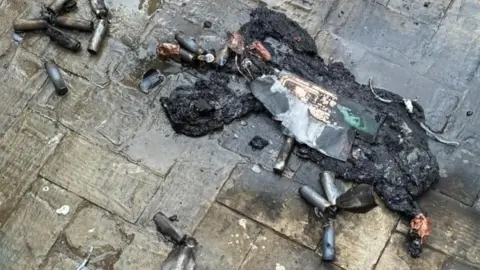 The remains of a e-scooter fire outside on the concrete.