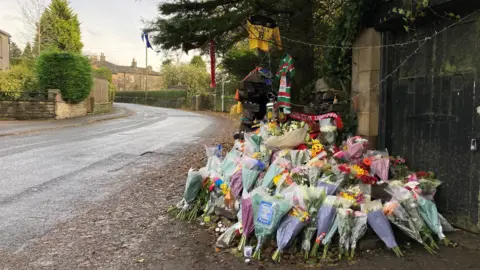 BBC/Charles Heslett Flowers left on side of road as a tribute 