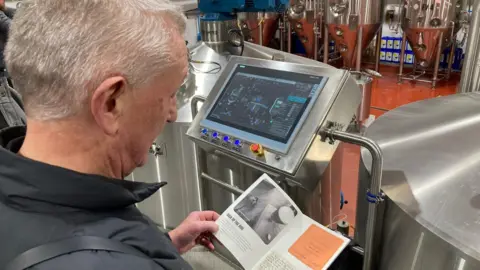 A man reading a pamphlet in a brewery 