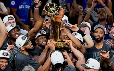 The New York Knicks hoist the trophy after defeating the San Antonio Spurs in game five of the 2026 NBA Finals to win the 2026 NBA Championship at Frost Bank Center. 