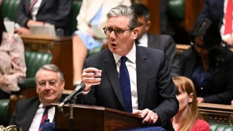 Keir Starmer, who has grey gelled hair and wears black glasses, speaks at the despatch box in the Commons as MPs look on