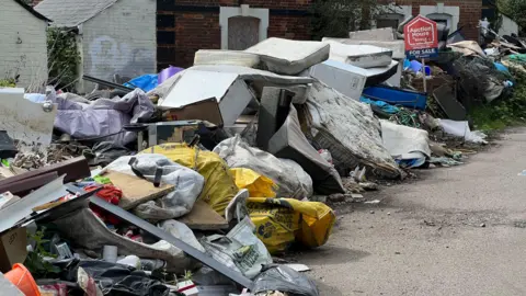 Thomas Magill/BBC A close-up of the fly-tipped rubbish piled up in front of the house.