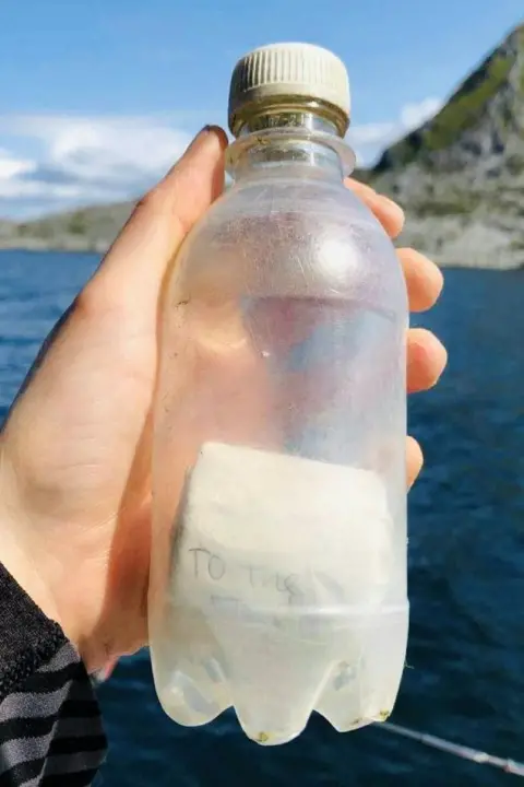 Pia Brodtmann Message in a bottle, being held by a hand.