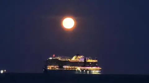 BBC Weather Watcher Stacey Johns Gosport with cruise ship passing glowing Strawberry Moon