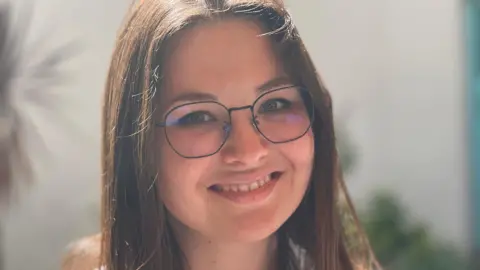 Dr Anastasiia Sabadosh. She has dark brown hair and glasses with thin black frames. She is pictured looking directly at the camera and smiling.