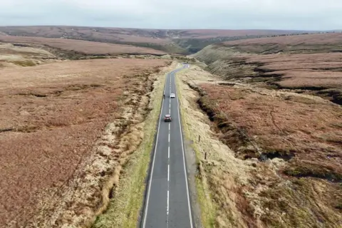 Dua mobil menyalip pengendara sepeda di sepanjang Snake Pass Summit